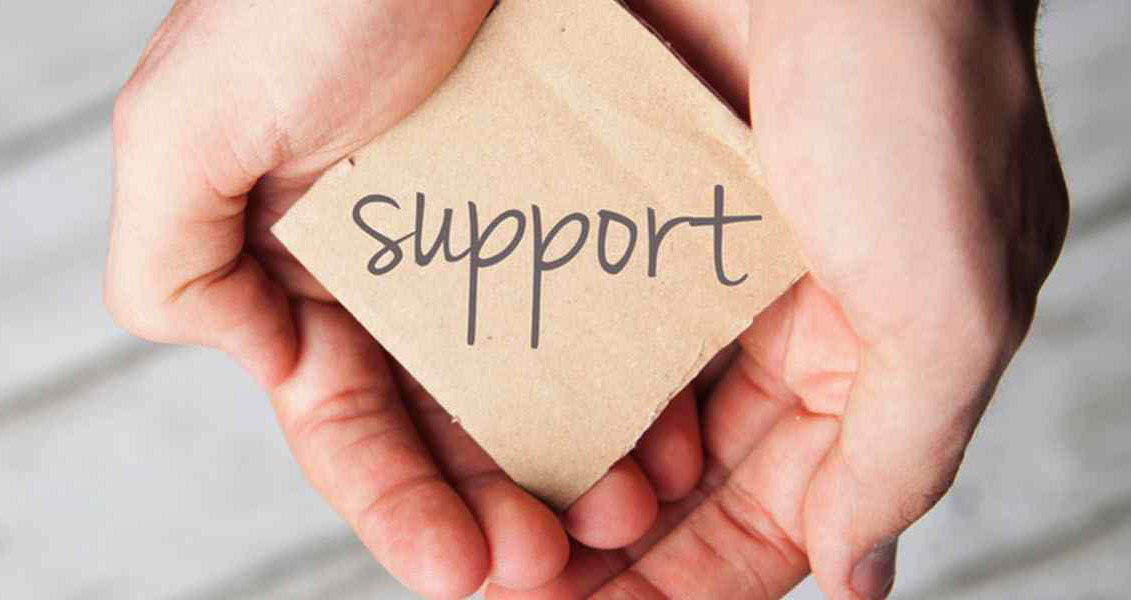 cupped hands holding a square of paper that reads "support"