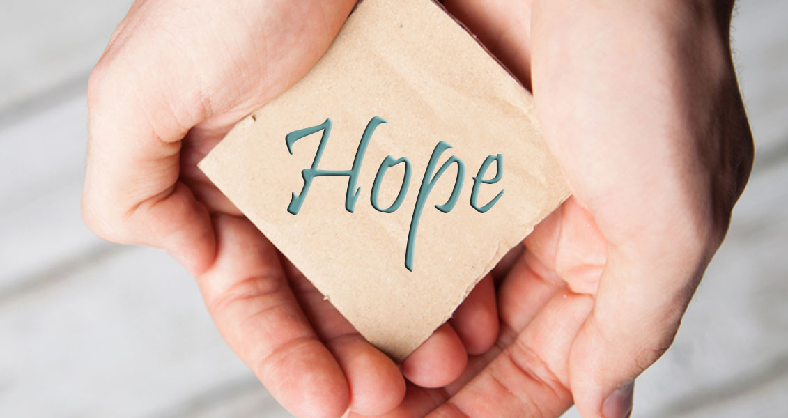 cupped hands holding a square of paper that reads "hope"